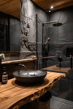 a black bowl sink sitting on top of a wooden counter next to a walk in shower