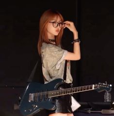 a girl with glasses is holding a guitar