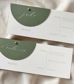 two green and white place cards with gold pins