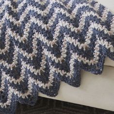 a blue and white crocheted blanket sitting on top of a couch