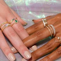 three women's hands with manicured nails and rings on their fingers, one is wearing