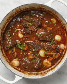 a pot filled with stew and potatoes on top of a table