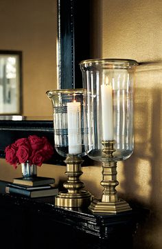 two candles are sitting on a table next to a mirror