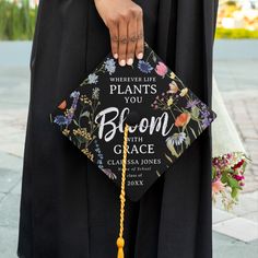 a woman wearing a black graduation cap and tassell with flowers on it that says, wherever life plants you bloom with grace