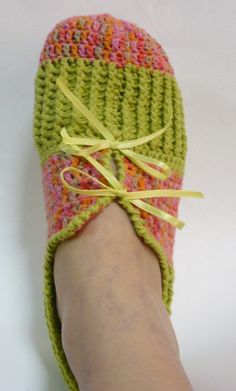 a person's foot wearing crocheted slippers with yellow ribbon