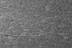 a black and white photo of a person on a skateboard in front of a brick wall