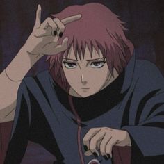 an anime character with pink hair pointing to his left ear and holding a cell phone in one hand