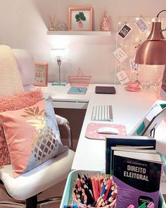 a white desk topped with lots of pink and blue items next to a chair filled with books