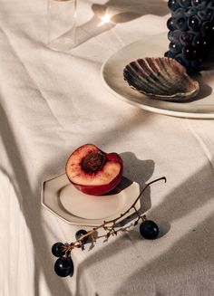 an apple is sitting on a plate next to some wine glasses and grapes are in the background