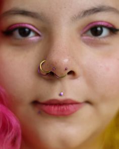 a woman with pink hair and piercings on her nose wearing a fake nose ring