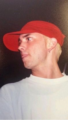 a young man wearing a red hat and white t - shirt looking off to the side