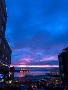 people are walking down the street in front of some buildings at dusk with lights on