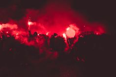 a large group of people standing around with red lights on their faces and hands in the air