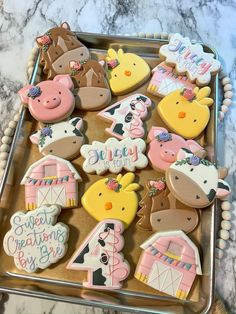 decorated cookies in the shape of farm animals and barnyards on a cookie sheet