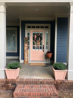 the front door of a blue house with two planters