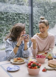 two women sitting at a table eating food