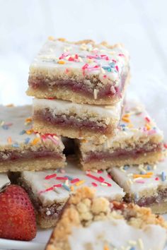 a white plate topped with lots of cookies and pastries next to a strawberries