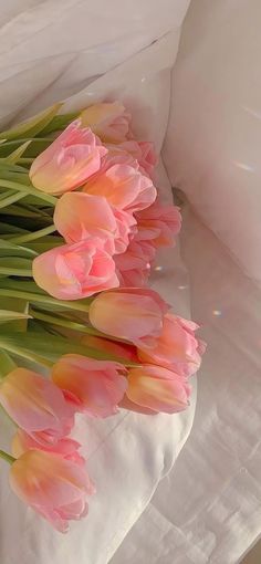 a bunch of pink tulips laying on top of a bed