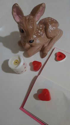 a deer figurine sitting on top of a table next to a card with hearts