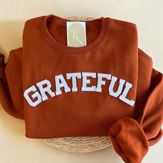 Cozy up with our Grateful Crewneck Sweatshirt this fall and Thanksgiving Season!  - Sweatshirt is super soft and comfy! ♡ - Sweatshirt composition: 50% cotton, 50% polyester - All our sweatshirts run a unisex fit. They are naturally oversized, so we normally recommend your true size. But if you like a more baggy look, we recommend sizing up. - These letters are iron-on patched and is heat pressed, not embroidered. But rest assured they've been tested and won't fall off! - Please note that crewne Maroon Tshirt Outfits Women, Cricut Fall Sweatshirt Ideas, College Letter Print T-shirt For Fall, Fall Cotton T-shirt, College Fall Cotton Sweatshirt, Cotton T-shirt For Fall, Brown Graphic Print Sweatshirt For Fall, Cotton T-shirt For College In Fall, Orange Everyday Top For Fall