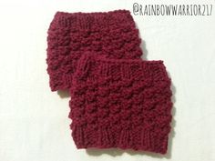 two crocheted red mittens sitting next to each other on a white surface