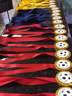 several medals are lined up on a table with red, white and blue ribbons in the shape of soccer balls