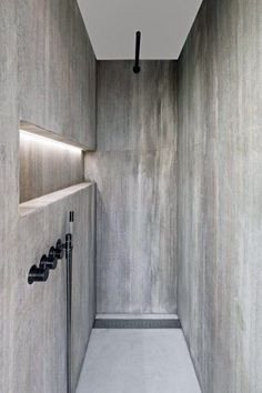 an empty bathroom with concrete walls and black fixtures on the wall, along with two hand held shower faucets