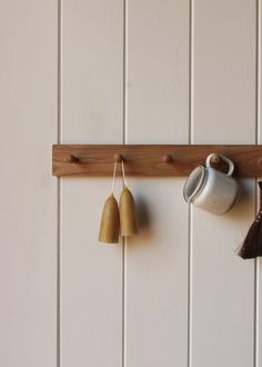 two cups hanging on a wall with some tassels attached to the hooks,