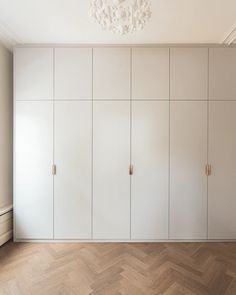 an empty room with white cupboards and a chandelier