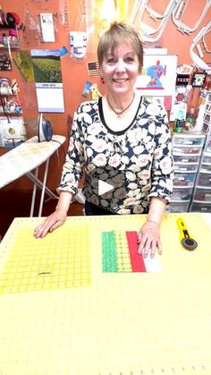 a woman standing in front of a large yellow piece of paper with scissors on it