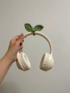 a person is holding up headphones with a plant on it's earbands