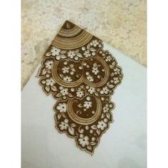 an intricately designed piece of paper on a table with white and brown laces