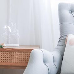 a chair with a pillow on top of it next to a table that has a lamp