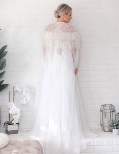 "It isn't enough to have feathers, you must dare to fly...." Add a touch of glamour to your bridal gown with this stunning Floor Length Tulle Beaded Cape with Ostrich Feather is a striking ivory color. With it’s floor length style, this ostrich feather statement piece is ideal for brides who are wanting something fabulous and show stopping on their wedding day. Hand Dyed Luxurious Ostrich Feather Cape Veil Clear Snap front closure Floor length style design with rounded front Made from Ethically Elegant Feather-trim Wedding Gown, Elegant Wedding Gown With Feather Trim, White Ostrich Feather Wedding Dress, Elegant Wedding Gown With Feathers, White Feathered Dresses For Wedding, Cape Veil, Feather Cape, Beaded Cape, Ostrich Feather