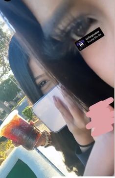 a woman taking a selfie with her cell phone and holding a drink in front of her face