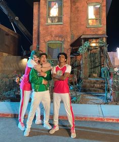 three young men standing in front of a brick building with a clock tower on top