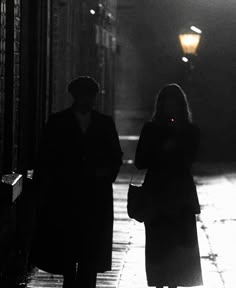 two people are walking down the street at night