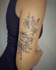 a woman with a tattoo on her arm is holding a book and flowers in it