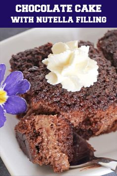 chocolate cake with nutella filling on a white plate next to a purple pansies