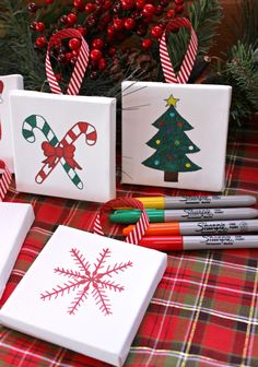 some christmas cards and markers are on a plaid tablecloth with candy canes in the background