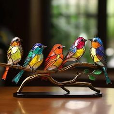 three colorful birds sitting on a branch with leaves