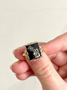 STUNNING bold and regal vintage yellow gold ring with a rectangular black onyx stone in the center and gorgeous scalloped ornate detailing beneath the gold pedestal holding the onyx up. The onyx bears a silver letter "B" on top with a small but mighty diamond stone in the corner. This is an incredible, highly sought-after art deco signet ring. This is estimated to be an antique piece. There is a symbol stamped inside the band beside which I cannot make out. This is presumably the maker's mark but possibly also the gold content. It appears to be a triangle, which apparently has roots in England and may even indicate a higher gold content, such as 14K. Size is approximately 6 - 6.25. Total weight is approximately 2.59 grams. *Note: This listing will ship with TRACKING to ALL destinations, in Luxury Black Victorian Style Signet Ring, Luxury Vintage Signet Ring With Diamond Accents, Luxury Antique Signet Ring With Engraving Option, Luxury Engraved Onyx Ring, Luxury Vintage Signet Ring With Polished Finish, Black 14k Gold Engraved Jewelry, Engraved 14k Black Gold Jewelry, Engraved Black 14k Gold Jewelry, Personalized Black Jewelry For Anniversary