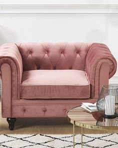 a living room with a pink velvet couch and coffee table in front of the wall