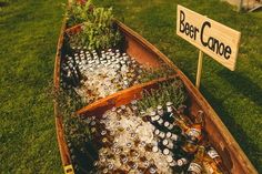 a wooden boat filled with beer bottles on top of a lush green field next to a sign that says deer dance