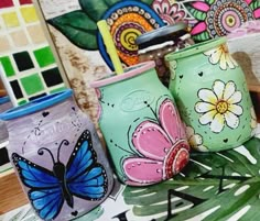 three painted jars sitting on top of a table