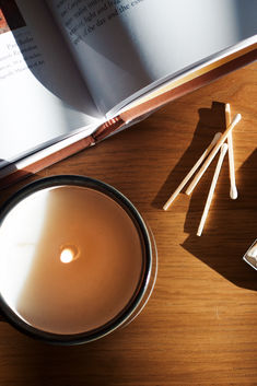 an open book on a table next to matches and a bowl with matchsticks