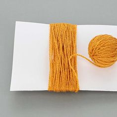 an orange ball of yarn sitting on top of a piece of paper