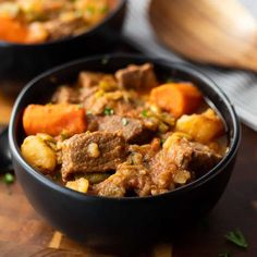 two black bowls filled with stew and carrots