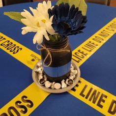 there is a vase with flowers in it on top of a police line tablecloth