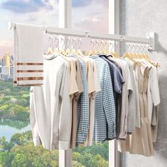 a rack with clothes hanging on it in front of a window overlooking a cityscape